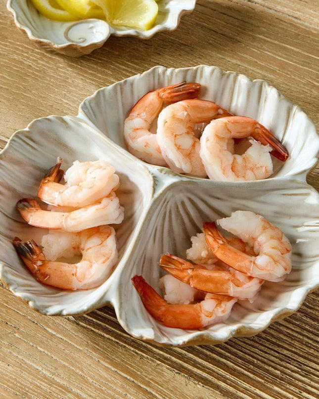 Three-shell dish with cooked shrimp on a wooden surface