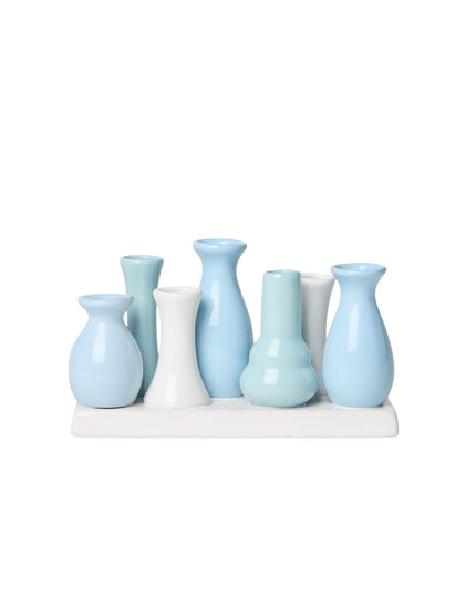 Set of light blue and white vases on a white stand against a white background