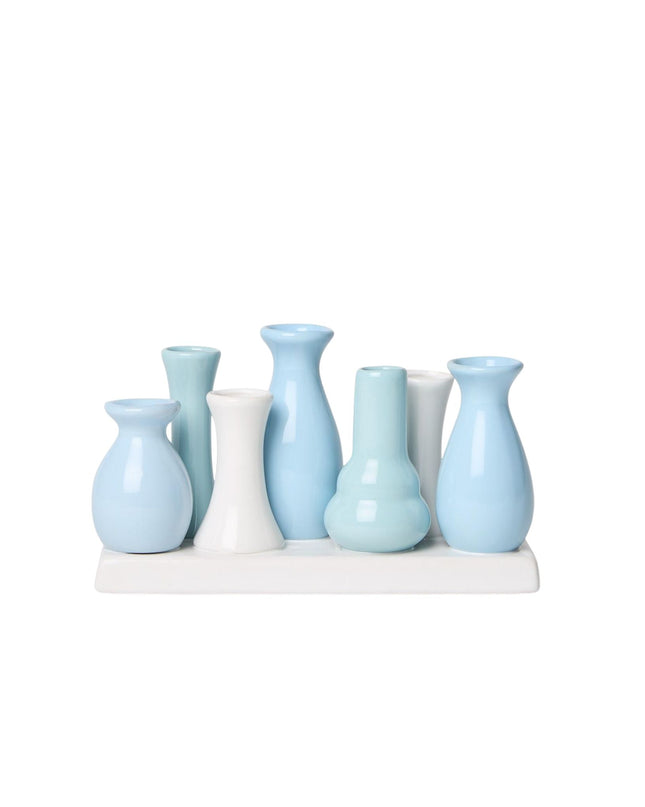 Set of light blue and white vases on a white stand against a white background