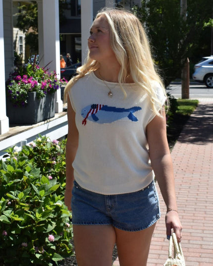 Woman wearing a white t-shirt with a blue graphic design outdoors.