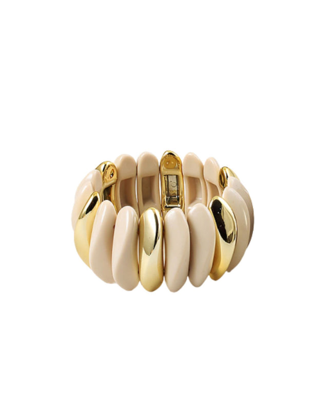 A wide, chunky cuff bracelet featuring alternating smooth, rounded segments in cream and polished gold-tone metal, shown on a plain white background.