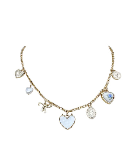 A gold-tone charm necklace featuring multiple heart-shaped charms, including a central light blue enamel heart, a bow charm, and textured silver-toned hearts, displayed on a plain white background.