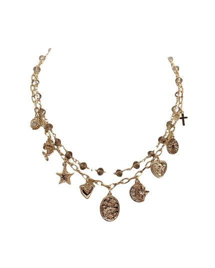 A gold-toned multi-strand chain necklace featuring various celestial and religious charms, including a cross, star, moon, and hearts, set against a plain white background.
