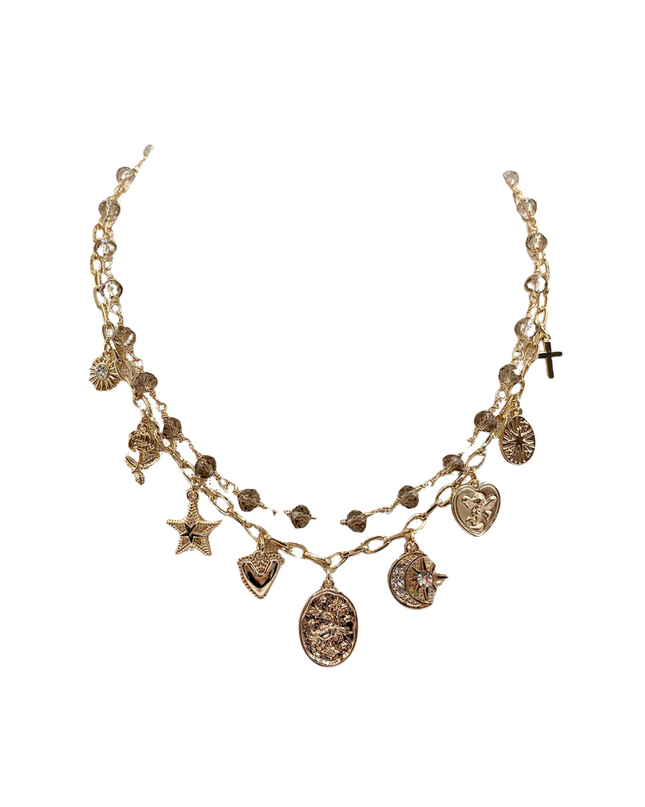 A gold-toned multi-strand chain necklace featuring various celestial and religious charms, including a cross, star, moon, and hearts, set against a plain white background.