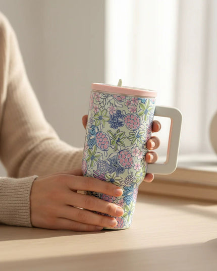 Person holding a floral-patterned tumbler with a light background
