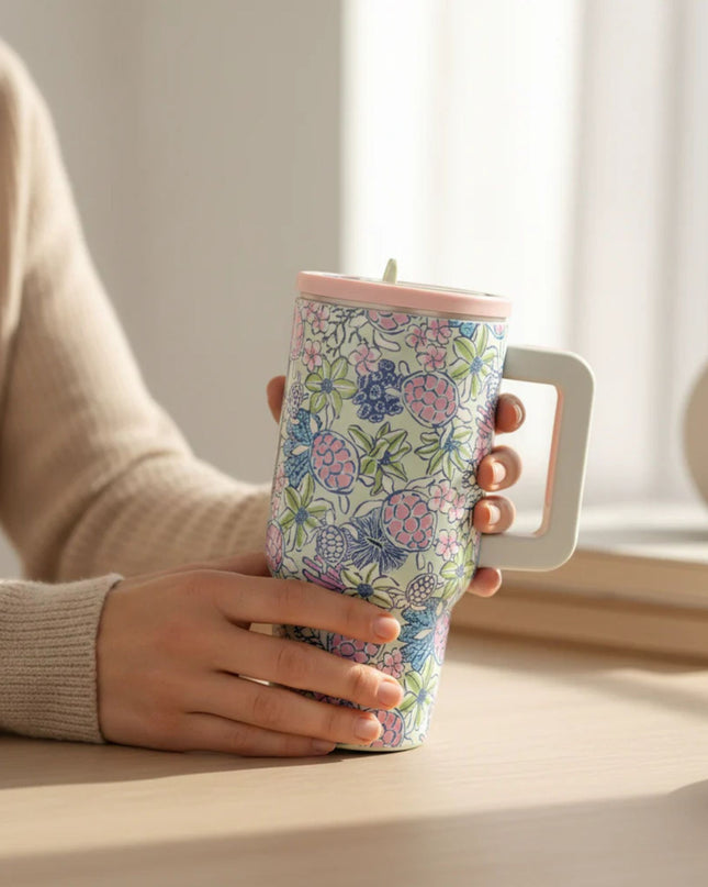 Person holding a floral-patterned tumbler with a light background